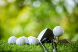 Golf balls, club, and tee on grass.