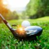 A golf club hitting a ball.