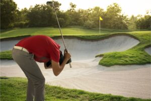 Frustrated golfer next to a sand trap.